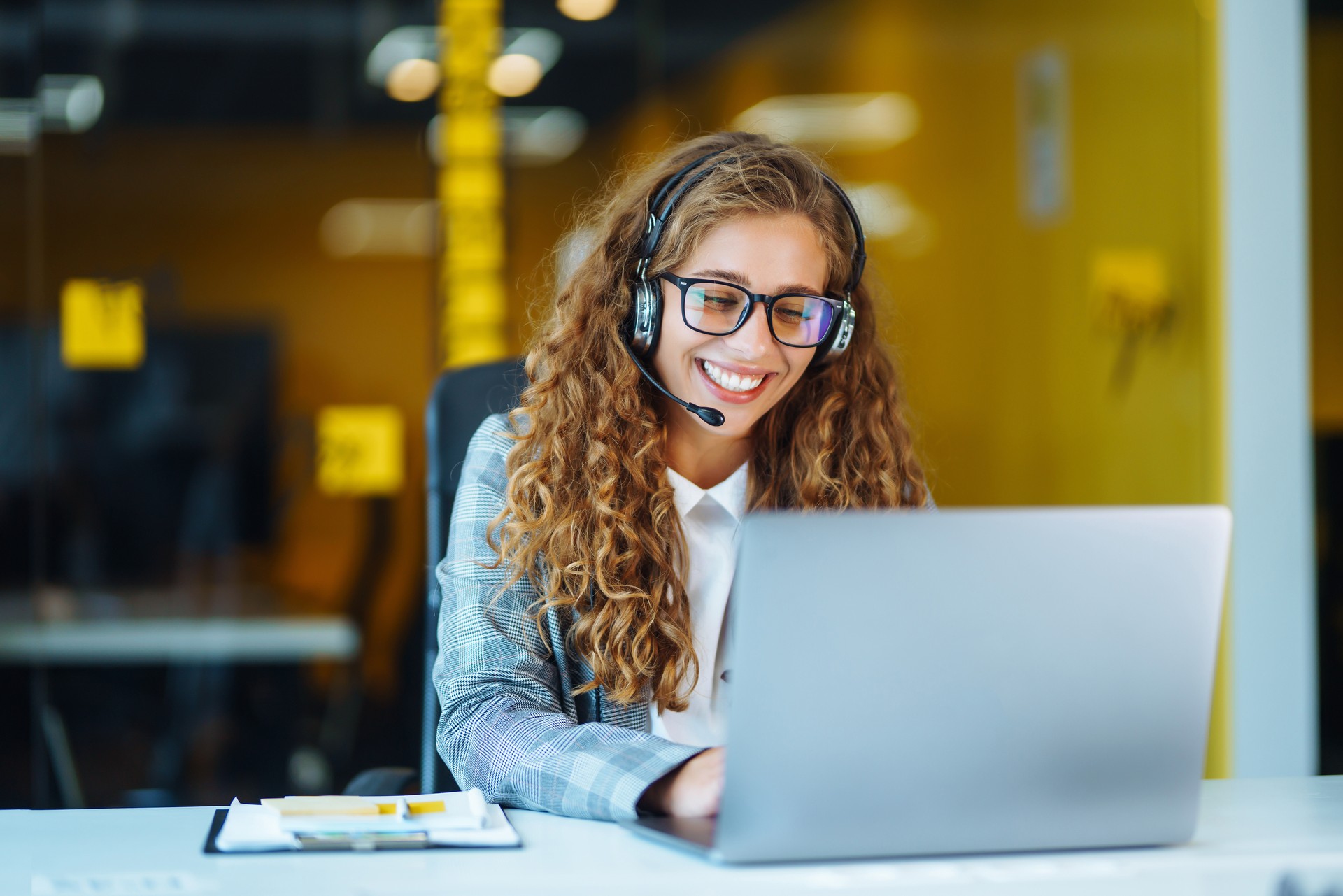 Call center agent with headset working on support hotline in modern office.